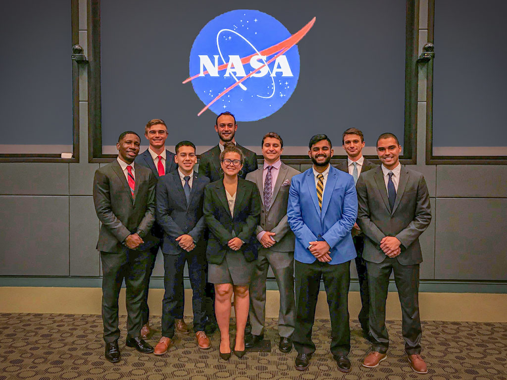 Ely and other interns pose in front of the NASA logo.