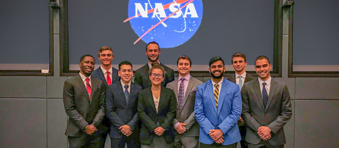 Ely and other interns pose in front of the NASA logo.