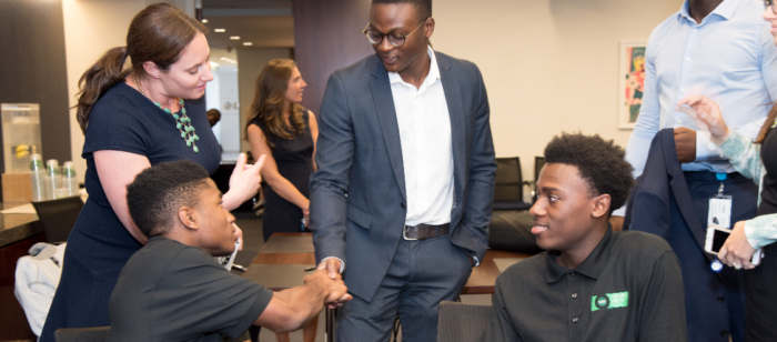 Two Black interns are introduced to a Black businessman.