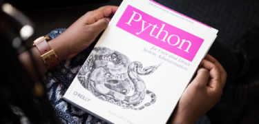A person holding a book titled "Python."