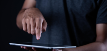 Close up of a person holding a tablet and pointing at it