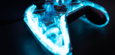 Gaming console remote lit in neon blue.