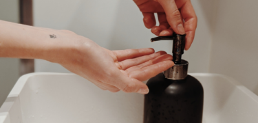 Two hands are preparing to put soap onto one hand from a soap dispenser.