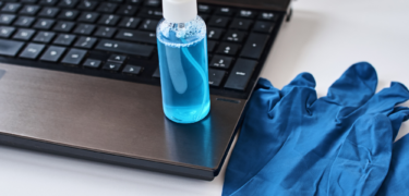 Sanitizer and gloves by laptop.