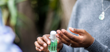 A woman is holding hand sanitizer and applying it on her hands.