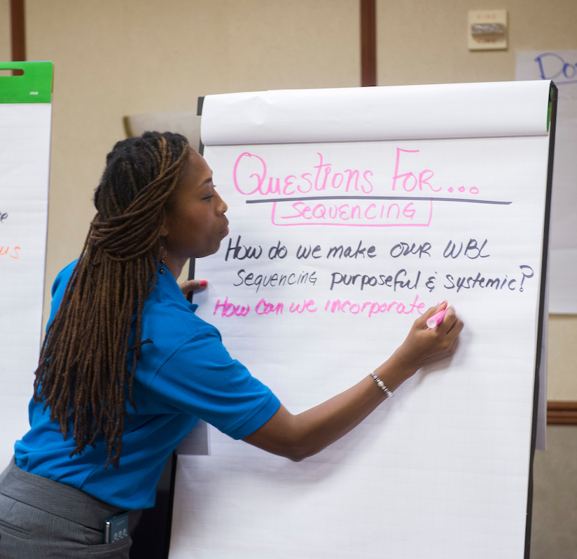 An educator writes questions on a large notepad about improving work-based learning for their NAF academy