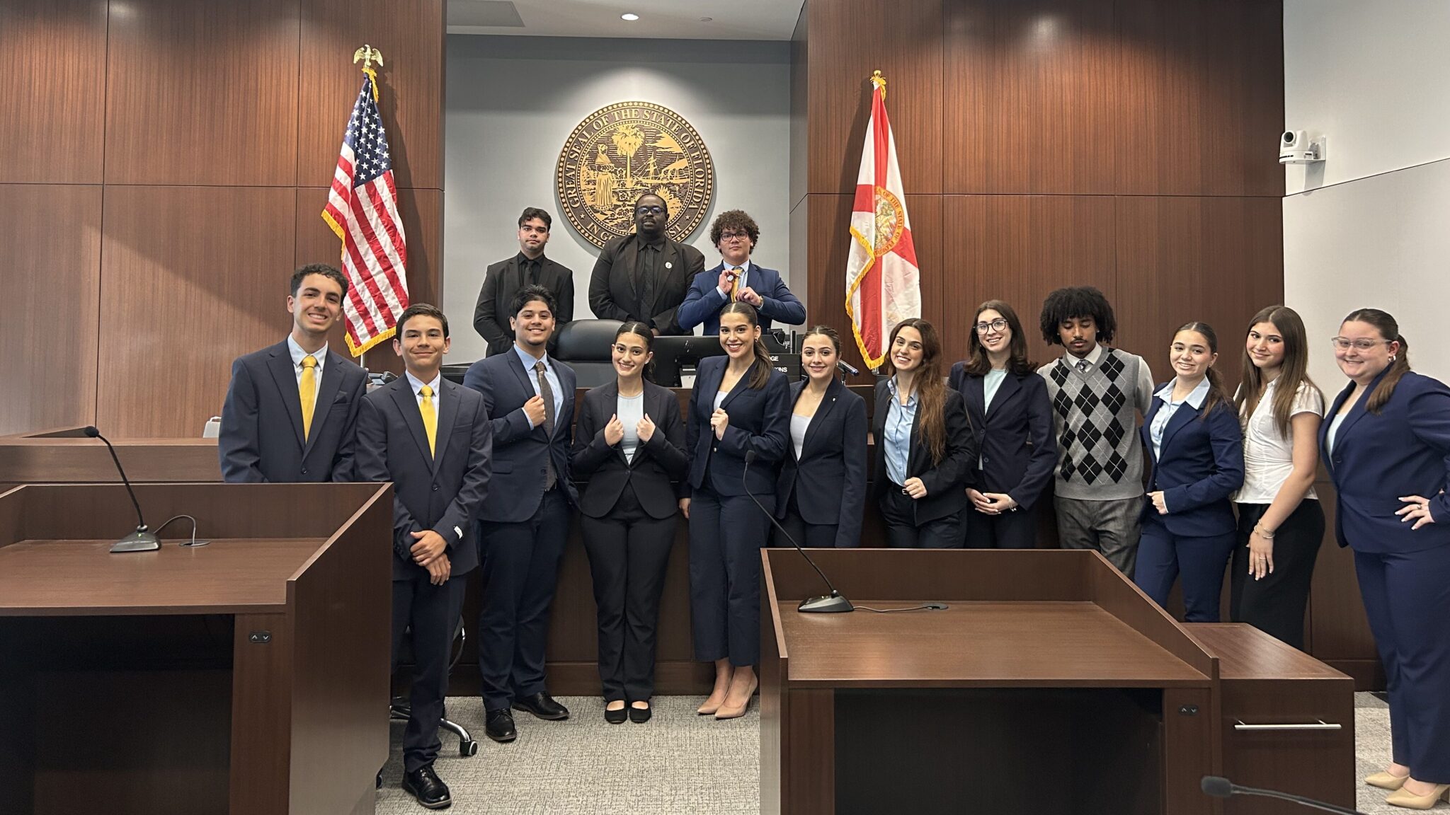 A group of NAF Academy of Law students in formal attire poses in a courtroom.